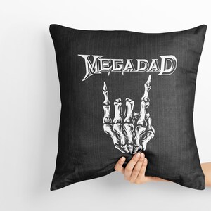 Może przedstawiać: Czarna poduszka z białym tekstem "Megadeth" i białą szkieletową ręką wykonującą gest rock and roll.