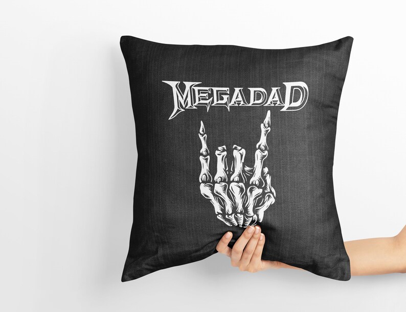 Może przedstawiać: Czarna poduszka z białym tekstem "Megadeth" i białą szkieletową ręką wykonującą gest rock and roll.
