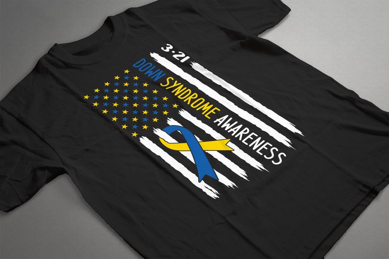 Może przedstawiać: Czarny T-shirt z wzorem biało-niebieskiej flagi amerykańskiej. Flaga ma ż&oacute;łto-niebieską wstążkę w środku i napis "3.21 Down Syndrome Awareness".