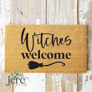 May include: A brown coir doormat with the text "Witches welcome" in black lettering. A black silhouette of a witch's broom is below the text.