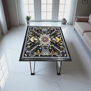Puede incluir: Una mesa de centro rectangular negra con un diseño incrustado detallado. La tapa presenta un patrón floral central con detalles azules, amarillos y blancos, rodeado de intrincados diseños y pájaros coloridos. La mesa tiene patas de metal negro.