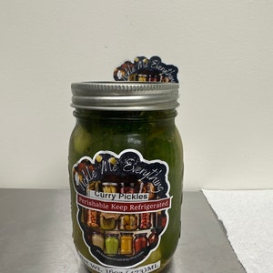 K&ouml;nnte beinhalten: Ein Glas mit gr&uuml;nen Curry-Pickles. Das Glas hat einen silbernen Deckel und ein Etikett mit der Aufschrift "Curry Pickles" und "Perishable Keep Refrigerated". Das Etikett zeigt auch eine Collage von Gl&auml;sern und den Text "Pickle Me Everything."