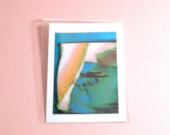 Op de afbeelding: Een rechthoekige kunstdruk in een doorzichtige plastic hoes. De print toont een abstracte compositie met een opvallend, gestructureerd, goudgeel verticaal element tegenover vervaagde kleurverlopen in diepblauw, groenblauw en zachtroze.
