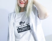 Unisex white tee with “Bird On Board, Board on Nerd”design. Rare side print included.