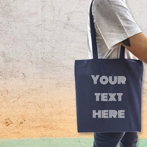 May include: A navy blue tote bag with white text that reads "YOUR TEXT HERE".