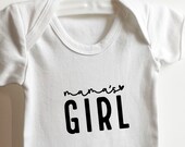 White 100% cotton baby vest with "Mama’s Girl" design.