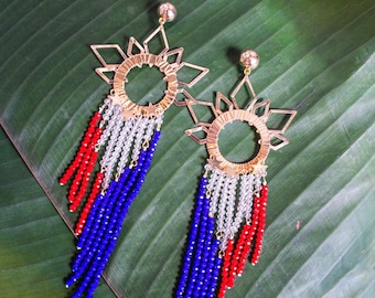 May include: A pair of gold earrings with a starburst design and dangling blue, red, and white beads.