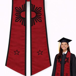 May include: Red graduation stole with black trim, featuring a sunburst design and stars. The stole is worn by a person in a graduation gown. The sunburst and stars are black. The stole is a symbol of academic achievement.