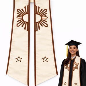 May include: Cream-colored graduation stole with brown trim and sunburst and star designs. The stole is worn by a person in a black graduation gown and cap. The stole is a symbol of academic achievement.