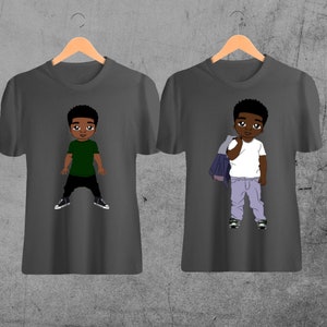 Pode incluir: Duas camisetas cinzas com ilustrações de desenhos animados de um menino pequeno. Uma camiseta apresenta um menino com uma camisa verde e calças pretas. A outra camiseta apresenta um menino com uma camisa branca, calças de ganga azuis e uma jaqueta de ganga.