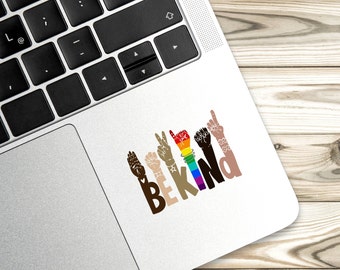 Puede incluir: Una pegatina con un diseño de arcoíris que dice "Be Kind" en letras negras. El diseño presenta múltiples manos en diferentes tonos de piel, cada una haciendo un gesto diferente.