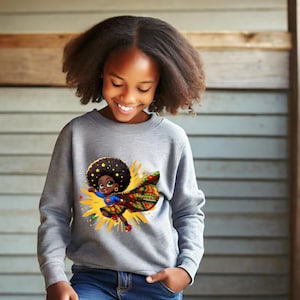 Könnte beinhalten: Ein graues Sweatshirt mit einem Cartoon-Superhelden-Design. Der Superheld hat eine große Afro-Frisur, einen bunten Umhang und einen gelben Hintergrund. Der Superheld trägt ein blaues Oberteil und einen Rock mit bunten Mustern. Das Sweatshirt wird von einer Person getragen.