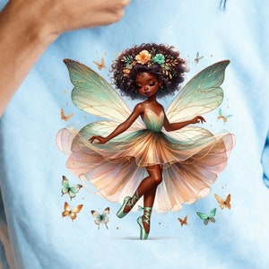 Könnte beinhalten: Eine fantasievolle Illustration einer Fee mit brauner Haut, die ein grün-goldenes Kleid und Ballettschuhe trägt. Sie hat braunes, lockiges Haar mit einer Blumenkrone und große grün-goldene Flügel. Die Fee ist von Schmetterlingen in verschiedenen Farben umgeben.