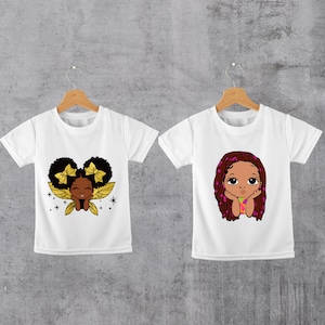 Peut inclure: Deux t-shirts blancs avec des motifs différents représentant des filles de dessin animé à la peau brune. Le premier t-shirt représente une fille avec des nœuds dorés dans les cheveux et des ailes. Le deuxième t-shirt représente une fille avec de longues tresses brunes.