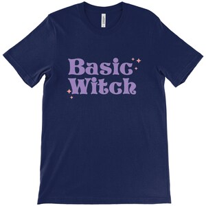 May include: A navy blue t-shirt with the text "Basic Witch" in purple with pink stars.