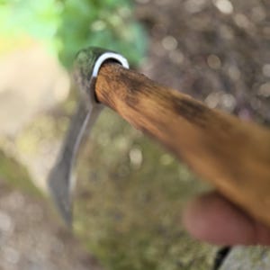 Op de afbeelding: Close-up van een tuinhark met een houten steel en een metalen blad. De steel is lichtbruin van kleur en het blad is zilver. De tool is ontworpen voor tuin- en landschapstaken.
