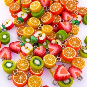 Peut inclure: Un assortiment de breloques en forme de fruits colorés, dont des oranges, des fraises, des kiwis et des pommes. Chaque breloque est dotée d'une boucle argentée pour l'attacher à des bijoux ou à d'autres créations artisanales. Les breloques sont de couleurs rouge, verte et orange.