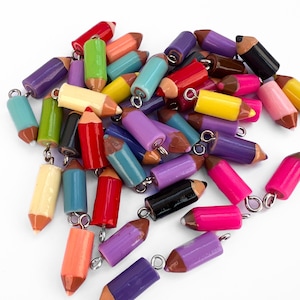 Peut inclure: Un ensemble de breloques en forme de crayons de couleur, dans des couleurs vives comme le rouge, le jaune, le violet et le vert. Chaque breloque est dotée d'une boucle argentée pour l'attacher à des bijoux ou à d'autres créations. Les crayons ont des pointes marron.