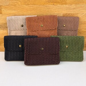 May include: A collection of six woven texture wallets in various colors: beige, rust, brown, black, dark brown, and olive green. Each wallet has a flap closure with a gold-colored button.