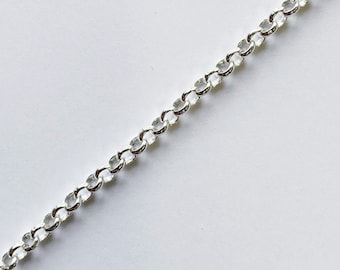 May include: A close-up of a silver-colored chain with oval-shaped links. The chain is diagonally positioned against a white background, showcasing its reflective surface and intricate design. This jewelry item is suitable for necklaces or bracelets.
