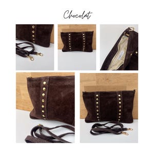 May include: A dark brown suede clutch with gold-colored stud accents. The bag has a detachable shoulder strap and the word "Chocolat" is written in cursive. The interior is a light beige color.