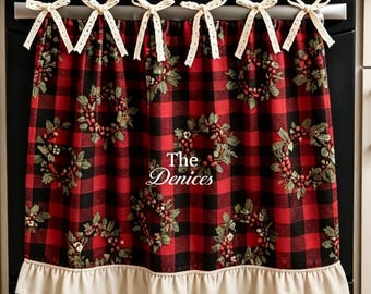 May include: A red and black buffalo plaid oven handle cover featuring a repeating wreath pattern, a ruffled cream-colored bottom hem, and six cream-colored fabric bows along the top. The text "The Denices" is printed in white in the center.