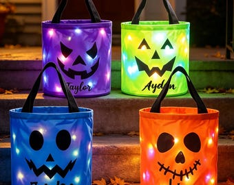 May include: Four cylindrical Halloween trick-or-treat buckets with black handles and internal LED lights. The purple bucket features the name Taylor, the green bucket says Ayden, the blue bucket says Jordan, and the orange bucket says Leina.