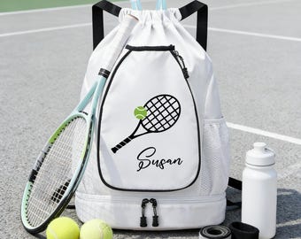 Puede incluir: Mochila de tenis blanca con un gráfico de raqueta y pelota de tenis negras, personalizada con el nombre "Susan". Incluye una raqueta de tenis, dos pelotas de tenis, una botella de agua y muñequeras. La bolsa tiene un cierre de cordón y un compartimento inferior con cremallera.