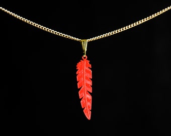 May include: A red feather pendant necklace with a gold chain. The feather is detailed and has a textured surface.