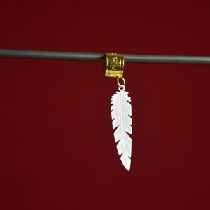 May include: A gold feather hair clip with a white feather charm. The feather charm is detailed with a textured design.