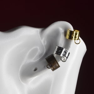 May include: Three ear cuffs with star designs. The cuffs are silver, gold, and bronze.