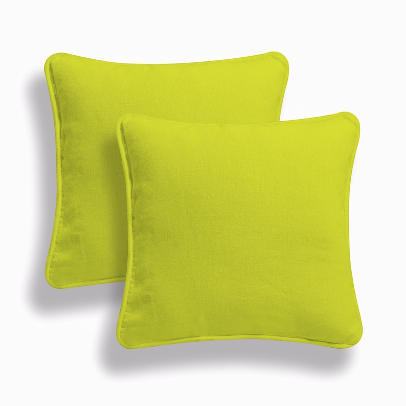 May include: Two lime green square throw pillows with a subtle texture. The pillows have a simple, modern design.