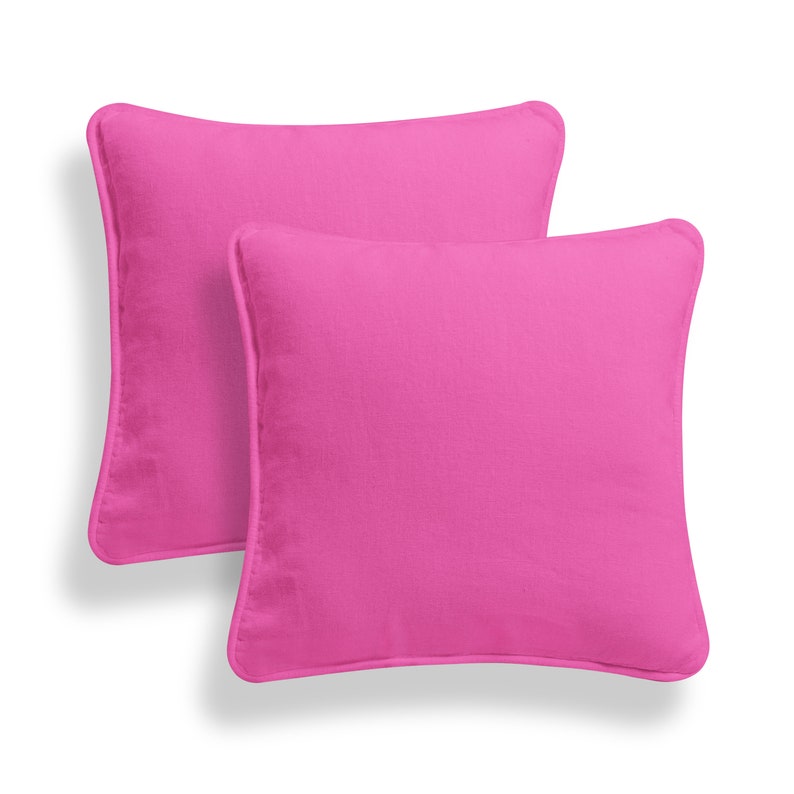 May include: Two pink square throw pillows with a simple design. The pillows are made of a soft, comfortable fabric.