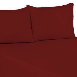 May include: Two burgundy pillowcases and a burgundy fitted sheet. The sheet is folded over the pillowcases.