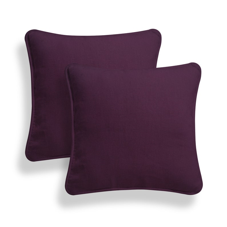 May include: Two purple square throw pillows with a subtle texture.