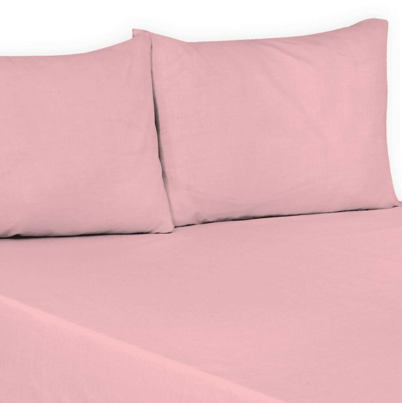 May include: Two pink pillowcases on a pink bed sheet. The pillowcases are made of a soft, smooth fabric.