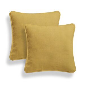 May include: Two mustard yellow square throw pillows with a subtle texture and a simple design.