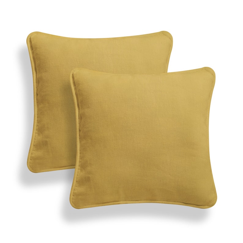 May include: Two mustard yellow square throw pillows with a subtle texture and a simple design.