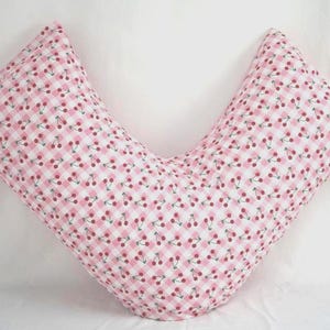 K&ouml;nnte beinhalten: Ein V-f&ouml;rmiges Kissen mit einem rosa-wei&szlig; karierten Muster, verziert mit kleinen roten Kirschillustrationen. Das Kissen ist f&uuml;r Komfort und Unterst&uuml;tzung konzipiert, wahrscheinlich f&uuml;r Schwangerschaft oder Stillen.