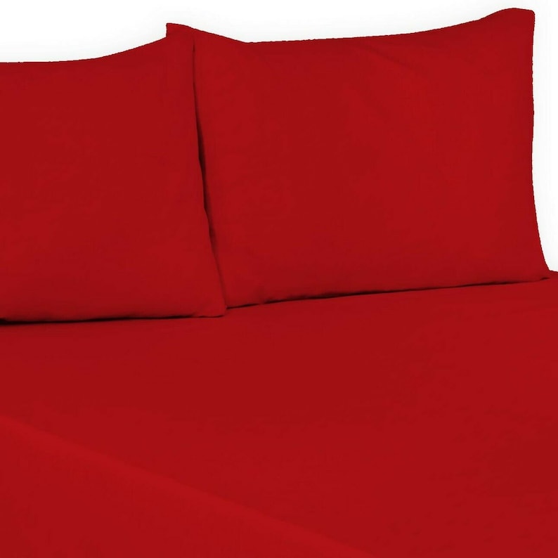 May include: Two red pillowcases and a red fitted sheet. The sheet is on a bed.