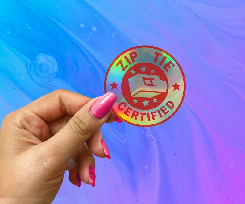 May include: A holographic sticker with a red circle and the text "ZIP TIE CERTIFIED" in white. The circle has a white outline and five white stars around the edge. Inside the circle is a white outline of a zip tie.