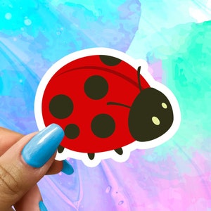 May include: A red ladybug sticker with black spots and a white outline. The ladybug is facing right and has a black head with white eyes.