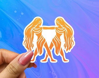May include: A sticker featuring an orange silhouette of two women standing back to back with their arms linked. The women have long flowing hair and are facing opposite directions.
