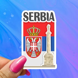 May include: A white sticker with the word "SERBIA" in black letters. The sticker features the Serbian flag with a coat of arms and a white monument.
