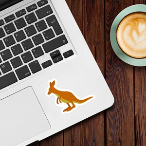 May include: A sticker of a cartoon kangaroo with orange fur on a white laptop.