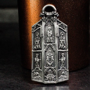 Metal pendant in religious art style, figure carving, saint with halo, design inspiration may come from church architecture, relief token