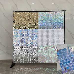 May include: A backdrop made of iridescent square sequins in gold, blue, silver, and white. The backdrop is made of four panels, each with a different color of sequins. The backdrop is on a stand and is ready to be used as a photo booth backdrop or for a party decoration.