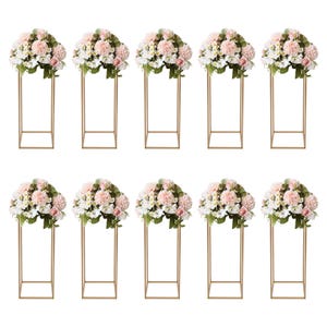 May include: Ten floral arrangements featuring pink and white flowers atop gold metal stands. The flowers are arranged in a full, rounded shape. The stands have a square base and a rectangular frame.