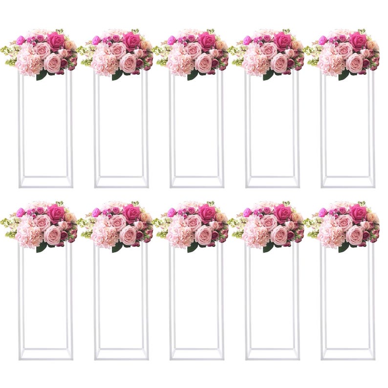 May include: Ten white metal floral stands, each topped with a bouquet of pink and light pink roses, hydrangeas, and greenery. The floral arrangements are arranged on rectangular stands, creating an elegant display for events.