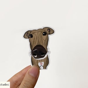 May include: A brown and white cartoon illustration of a dog's head with a pink heart on its chest. The dog is looking directly at the viewer.
